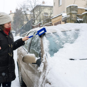 Woman cleans snow from her car